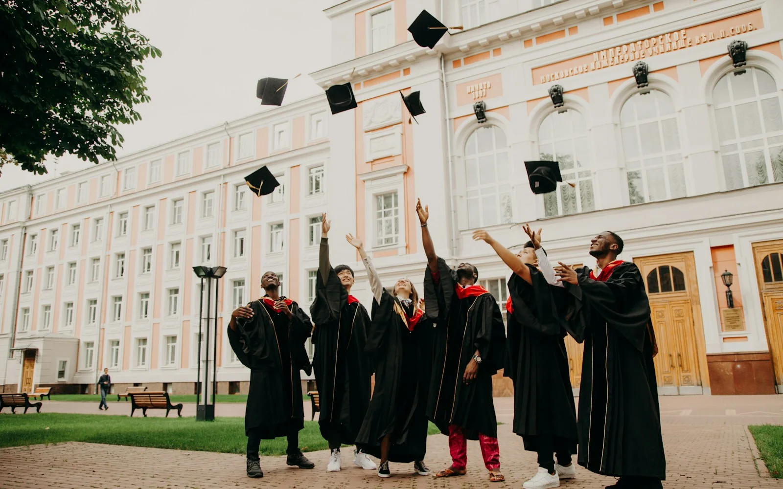 A group of graduates in black robes throwing their caps in the air